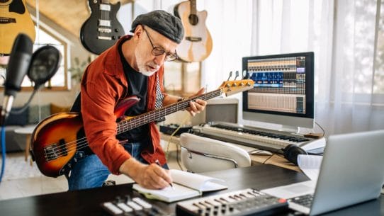 Developing A Bass Guitar Routine - Man holding bass guitar and taking notes while learning online