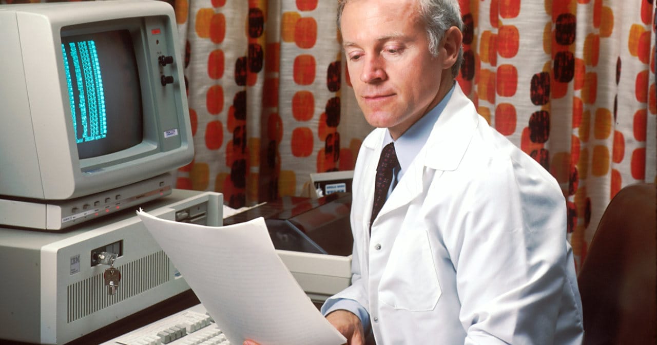 Person sitting by an old computer desktop doing keyword research - Image by National Cancer Institute