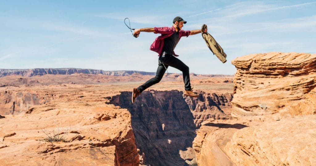 Person jumping a gap between canyon ledges - Image by Alex Radelich